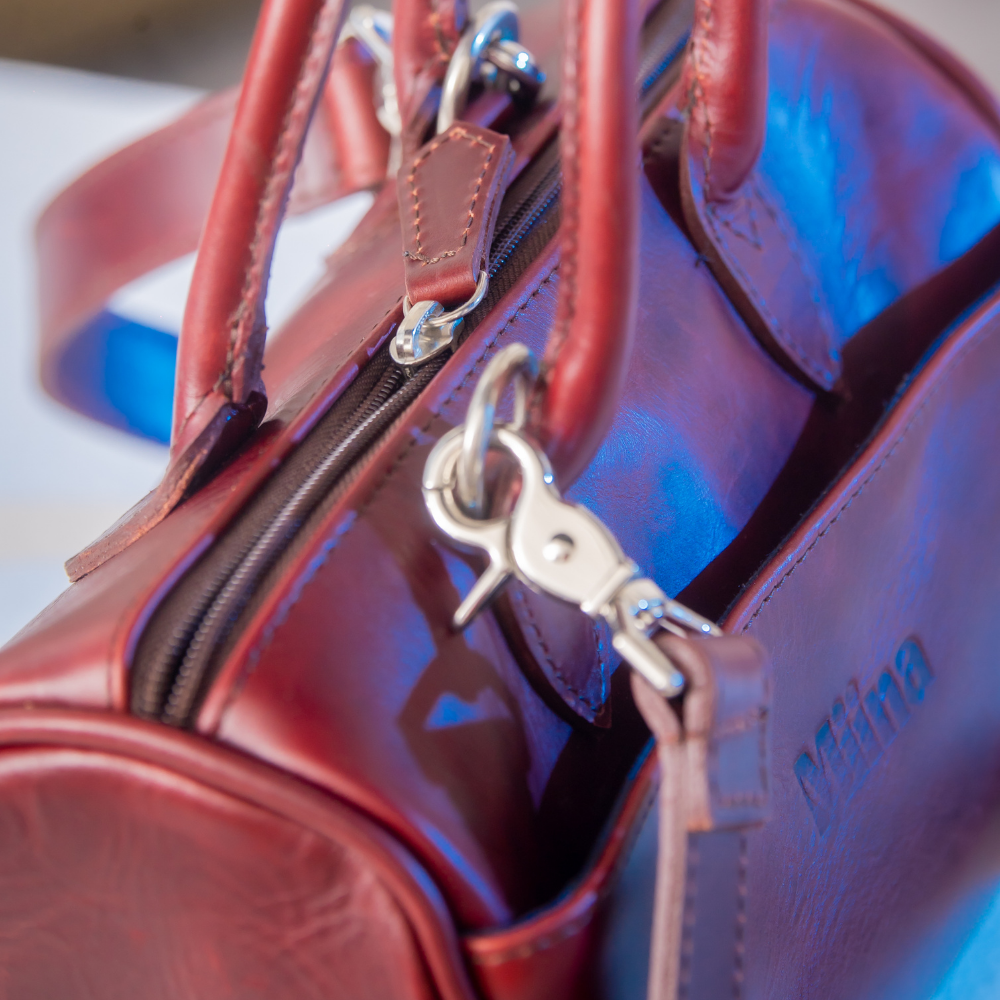 The Bella bowling handbag purse from Miina Goods in burgundy leather on white background and showing the closure for the cross body strap