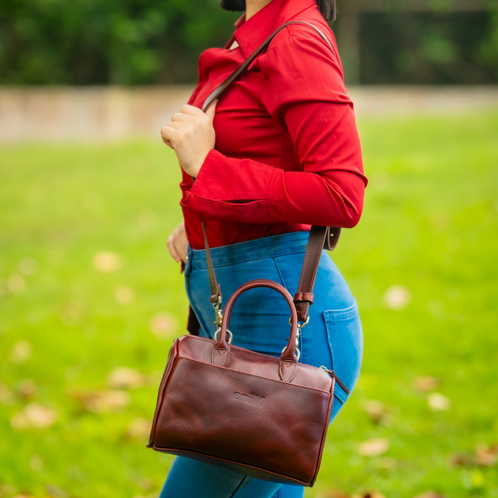 The Bella bowling handbag purse from Miina Goods in burgundy leather on model and shows the size of the purse relative to the body. 