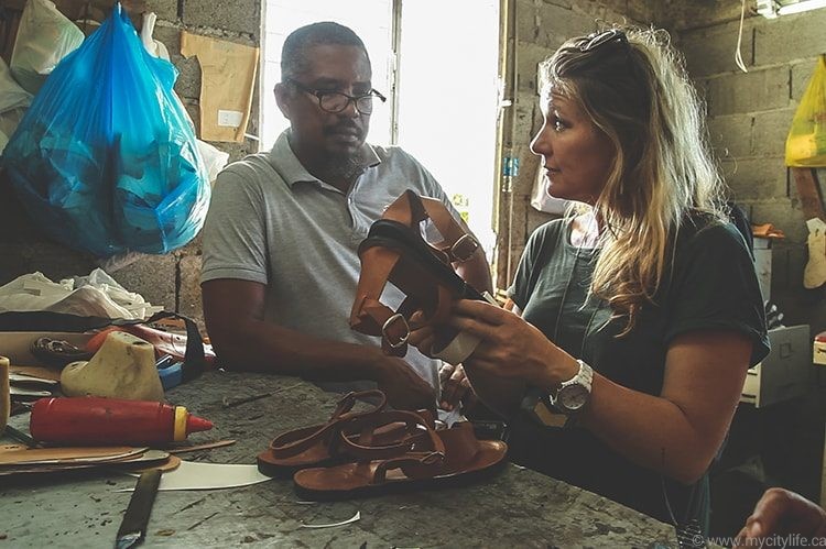 Two people working on leather items in a workshop setting.